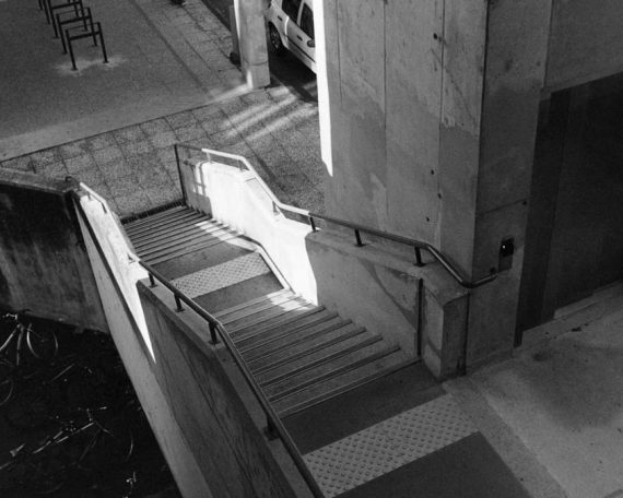 Black and white urban scene with concrete staircase and bicycles in Compiègne, France.